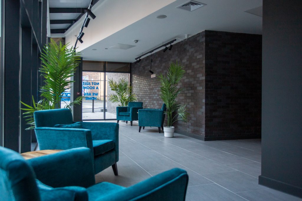 The Exchange Student Accommodation Liverpool - Reception area with 3 tall plants and 4 turquoise armchairs. 