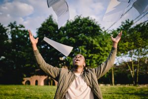 Student happy he is finished with exams, papers in the air