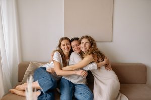 Three girlfriends hugging each other on a couch 